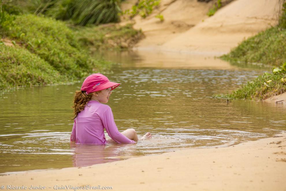 Imagem de uma menina nas águas calmas da Praia do Leão.